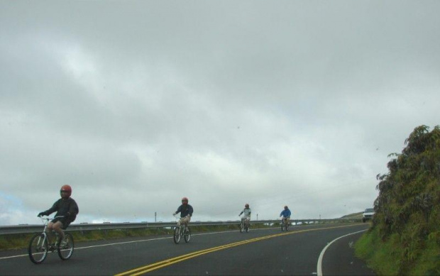 grupka rowerzystów wyłania się z za zakrętu, opuszcza mgłę, #Hawaje #Maui #wulkan