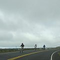 grupka rowerzystów wyłania się z za zakrętu, opuszcza mgłę, #Hawaje #Maui #wulkan